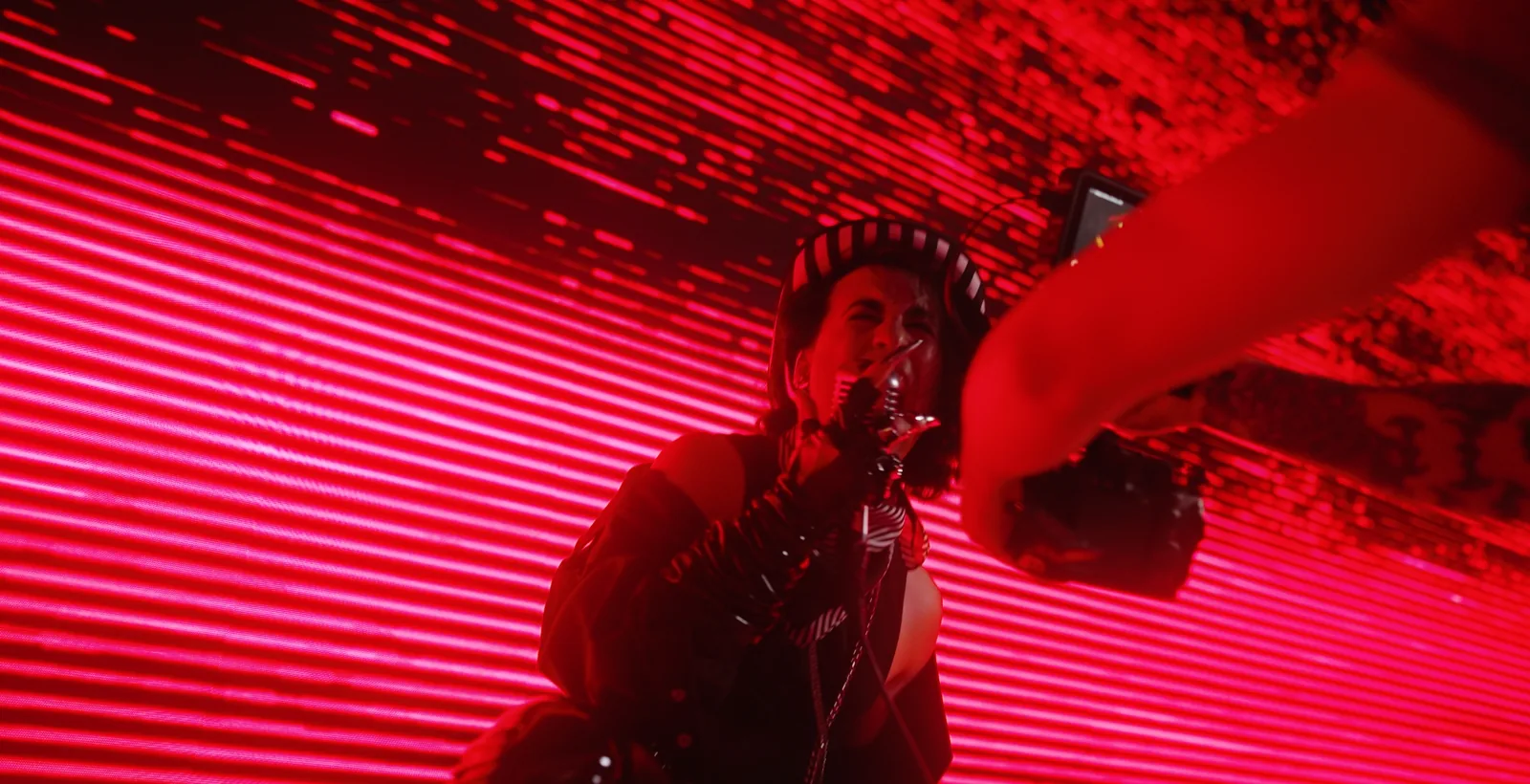 Music video shoot day: filming a singer in front of a red LED wall